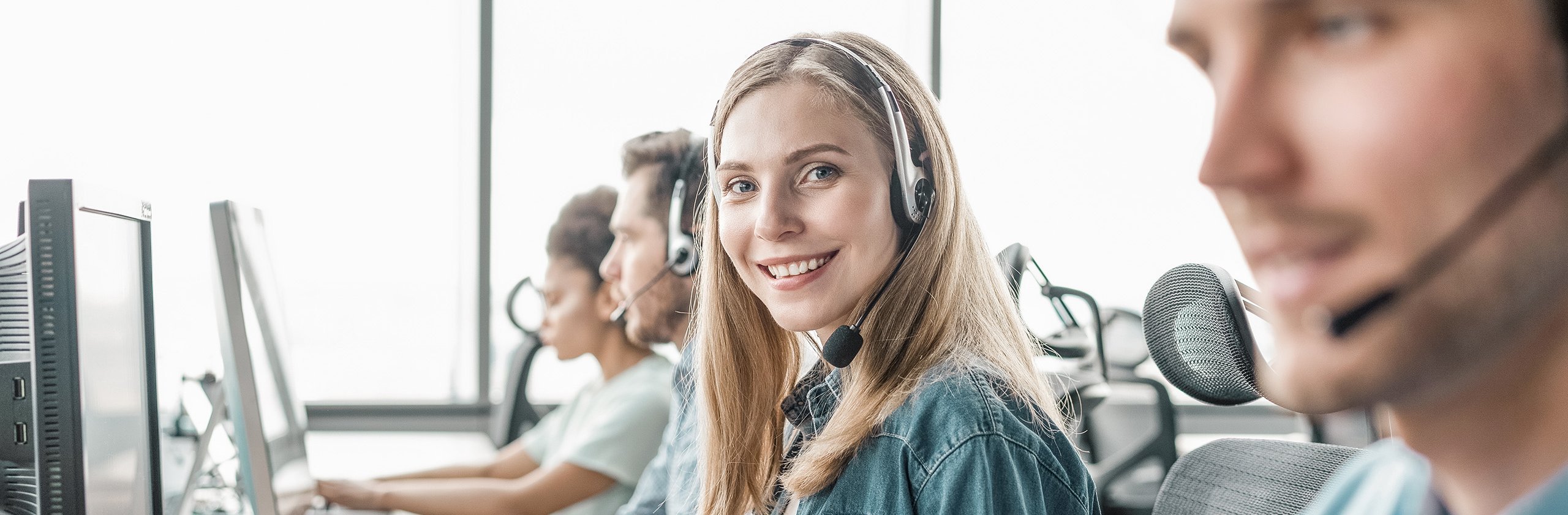 Young handsome customer support phone operator with headset working in call center.