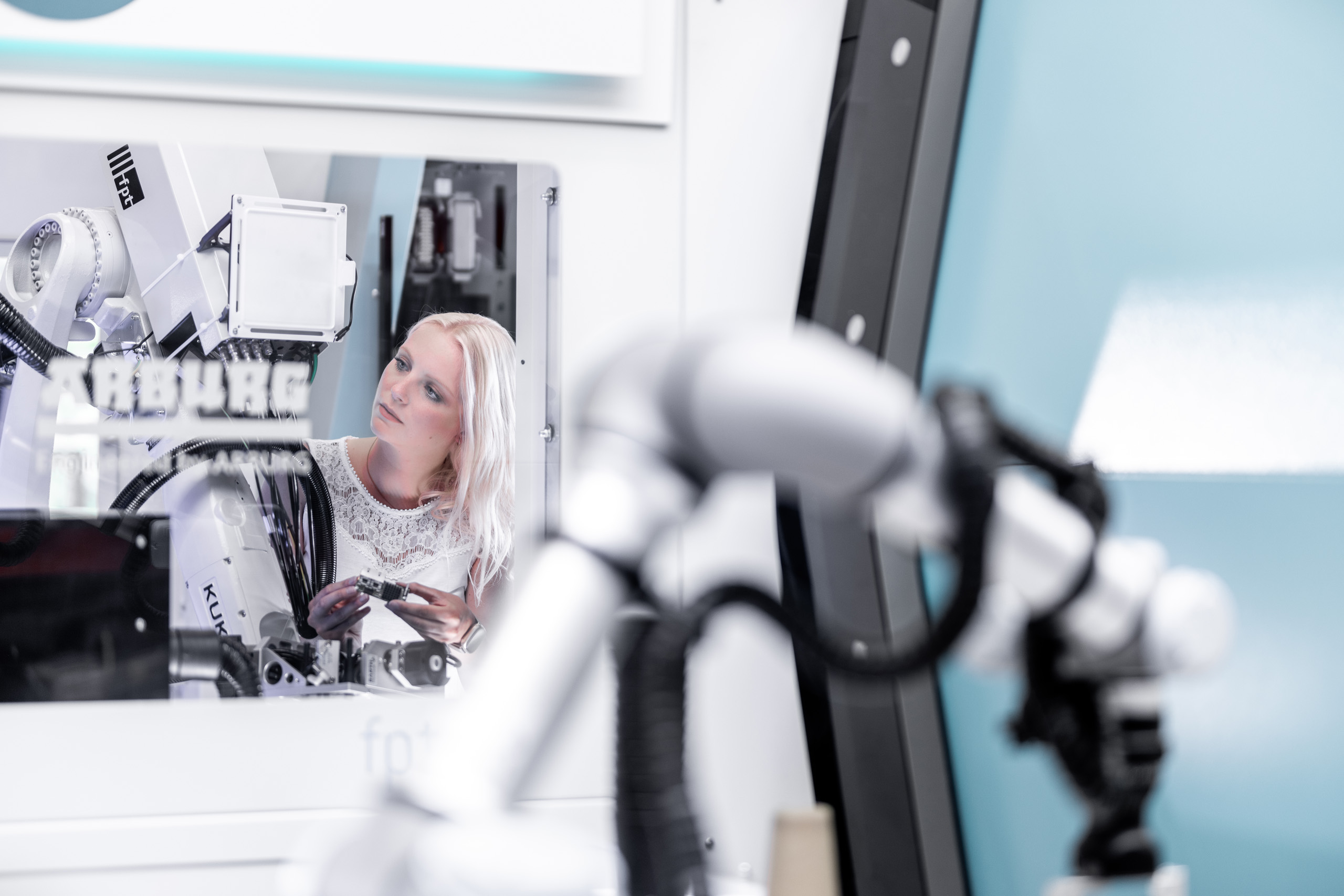 Ein Hilscher-Mitarbeiterin steht neben einem Roboter und hält ein comX-Modul.